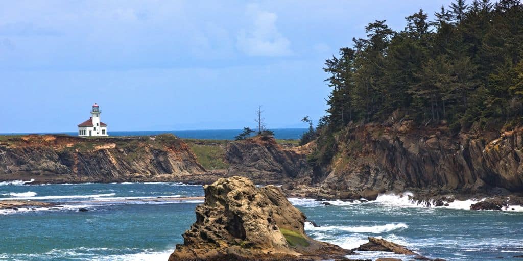 a lighthouse on top of a rocky outcropping near the ocean