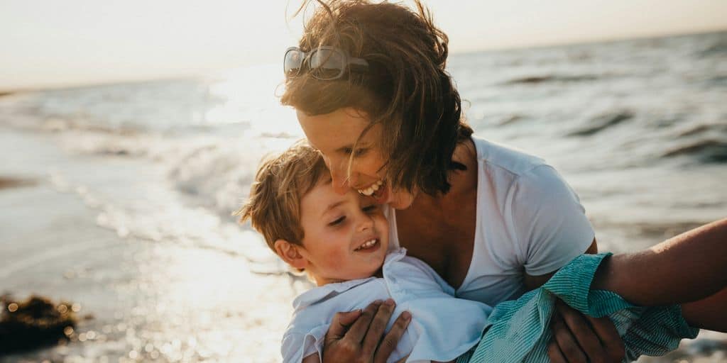 photo of mother and child beside body of water